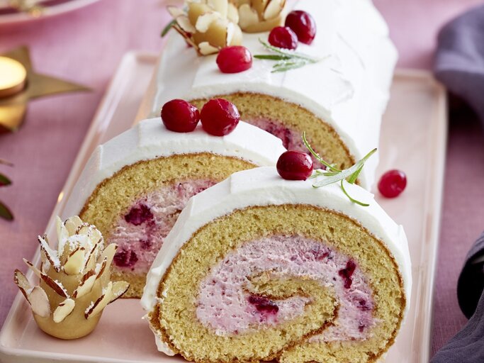 Auf einem Teller liegt eine  Marzipan-Cranberryrolle. Sie ist mit frischen Beeren und Marzipan verziert. | © EAT CLUB / Isabell Triemer