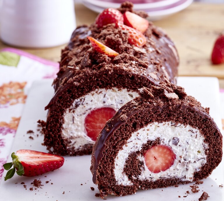 Auf einem Teller ist eine Maulwurf-Erdbeer-Biskuitrolle angerichtet. Sie ist mit Schokoglasur und Erdbeeren verziert. | © EAT CLUB / Isabell Triemer