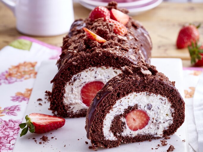 Auf einem Teller ist eine Maulwurf-Erdbeer-Biskuitrolle angerichtet. Sie ist mit Schokoglasur und Erdbeeren verziert. | © EAT CLUB / Isabell Triemer