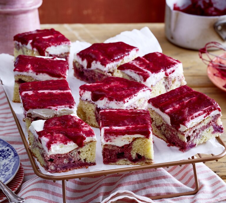 Beeren-Marmorkuchen vom Blech mit cremiger Frischkäseglasur, in Würfel geschnitten auf einem weißen Tuch.  | © EAT CLUB/Isabell Triemer