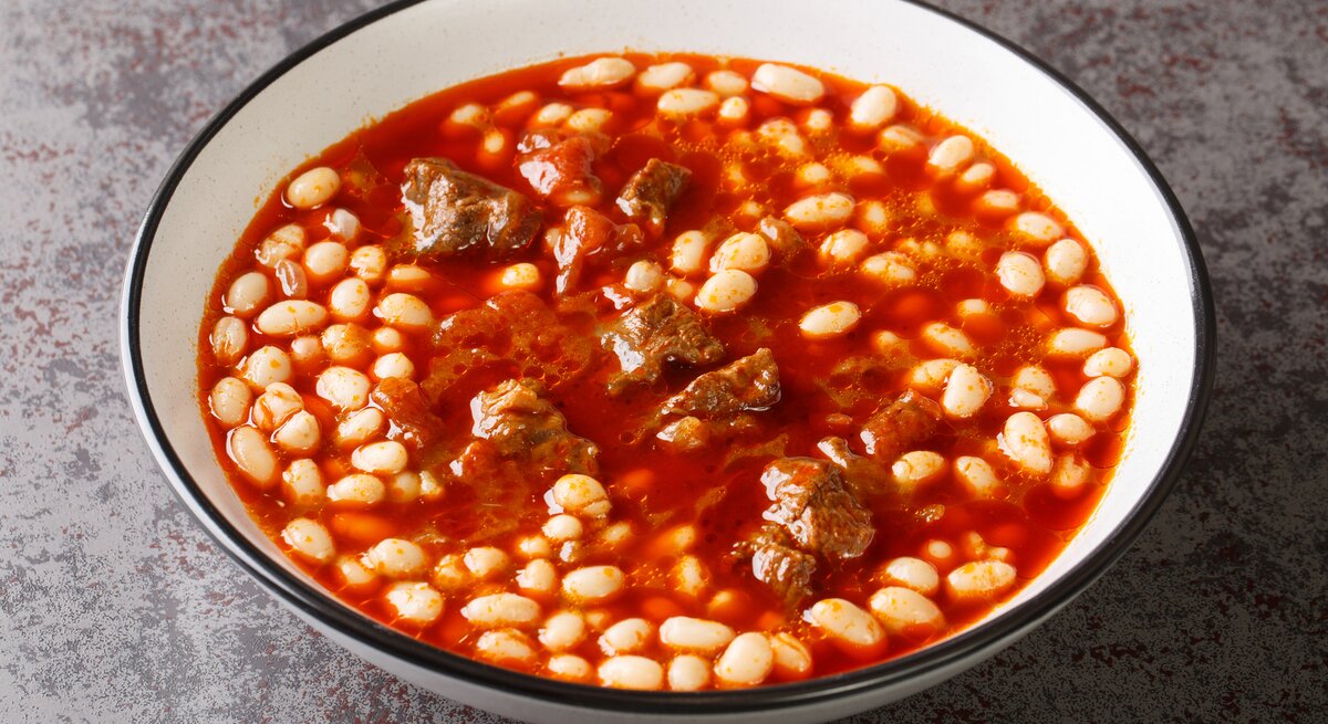 Ein weißer Teller mit türkischer Bohnensuppe auf einem grauen Teller.