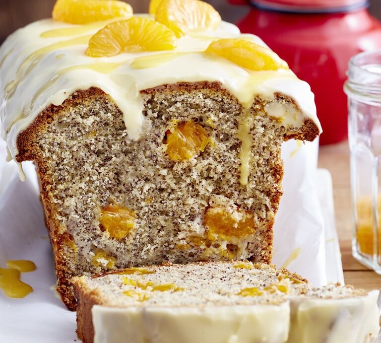 Auf einem Tisch steht ein angeschnittener Mohn-Eierlikör-Kastenkuchen. Er ist mit Mandarinen bedeckt.  | © EAT CLUB / Isabell Triemer