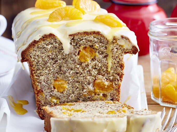 Auf einem Tisch steht ein angeschnittener Mohn-Eierlikör-Kastenkuchen. Er ist mit Mandarinen bedeckt.  | © EAT CLUB / Isabell Triemer
