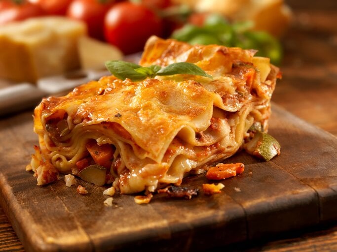 Angeschnittenes Stück Lasagne auf einem Holzbrett.  | © istock/Lauri Patterson