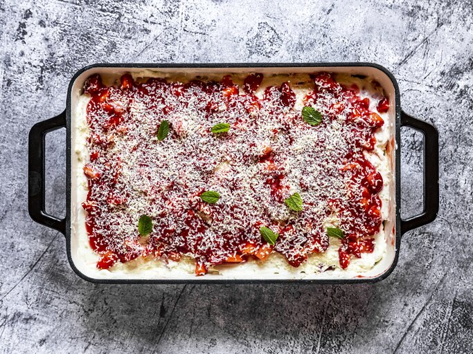 Von oben Ansicht einer Erdbeer-Lasagne, bestreut mit Schokoraspel aus weißer Schokolade. | © Getty Images/lacaosa