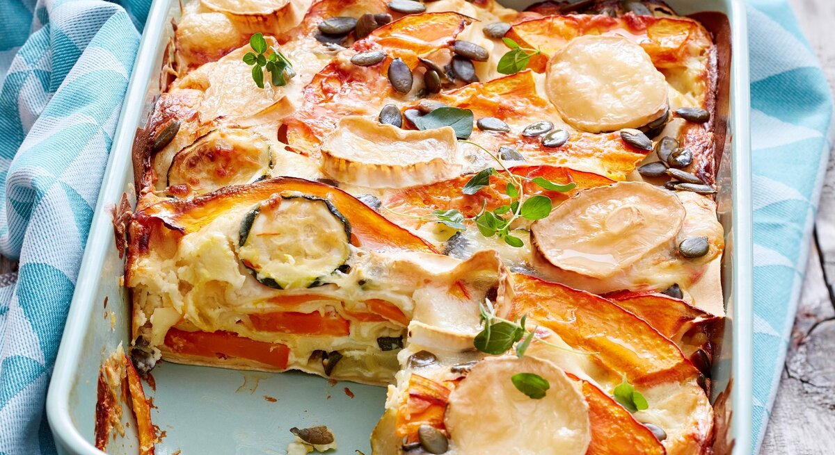 In einer Auflaufform ist eine Kürbis-Ziegenkäse-Lasagne angerichtet. Sie ist mit Käse und Gemüse gebacken. 