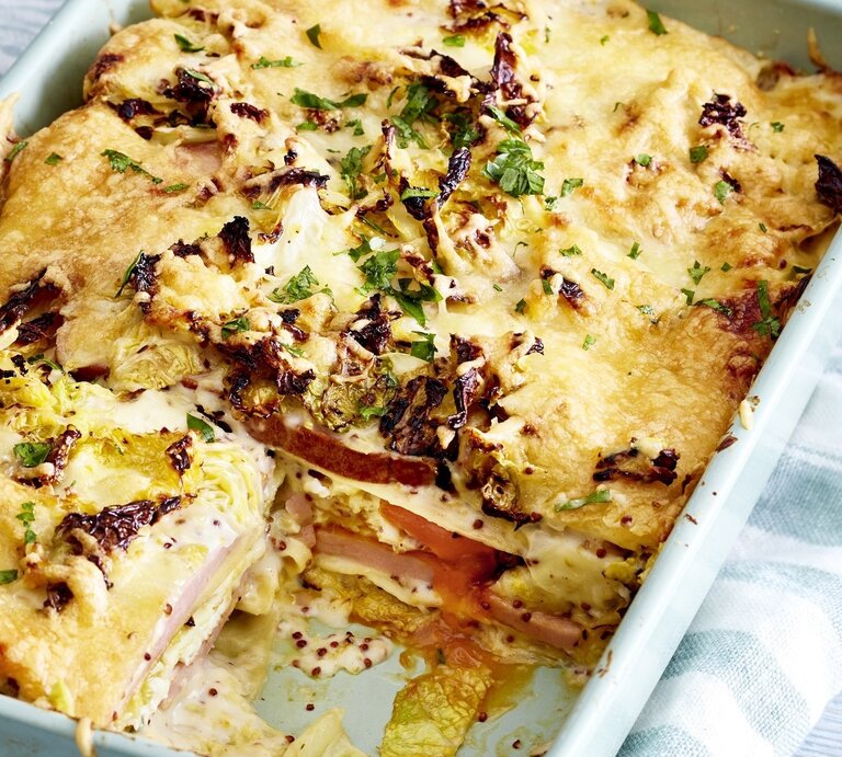 In einer Auflaufform ist eine Fleischkäse-Lasagne mit Wirsingrahm angerichtet. Sie ist mit Kräutern überstreut. | © EAT CLUB / Isabell Triemer