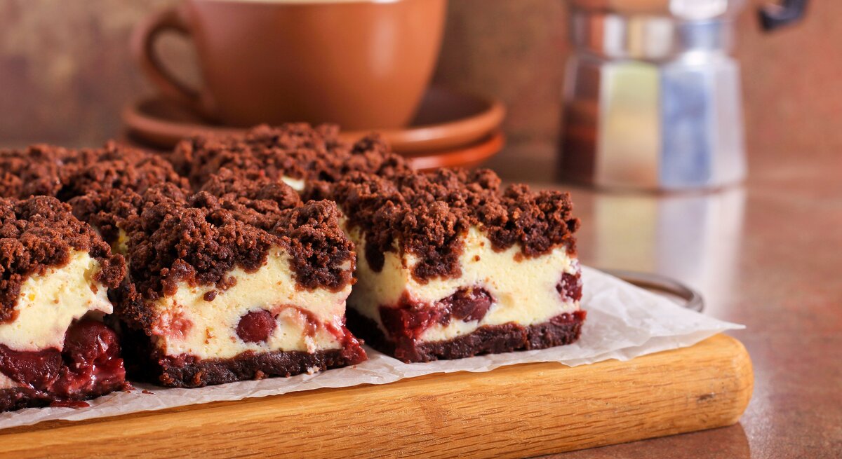 Kirsch-Käsekuchen mit Schokostreusel auf Holzbrett.