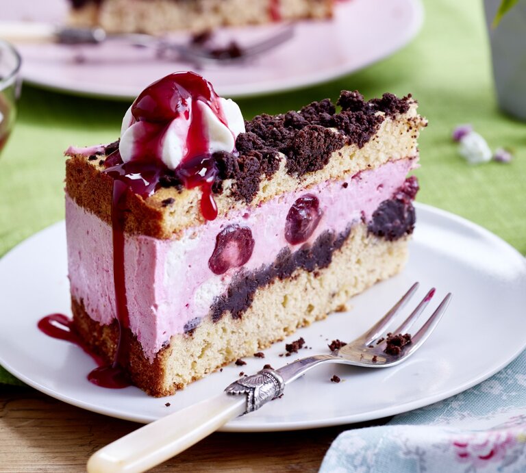 Auf einem Teller steht ein Stück Kiba-Streuseltorte. Es ist mit einem Klecks Schlagsahne verfeinert. | © EAT CLUB / Isabell Triemer