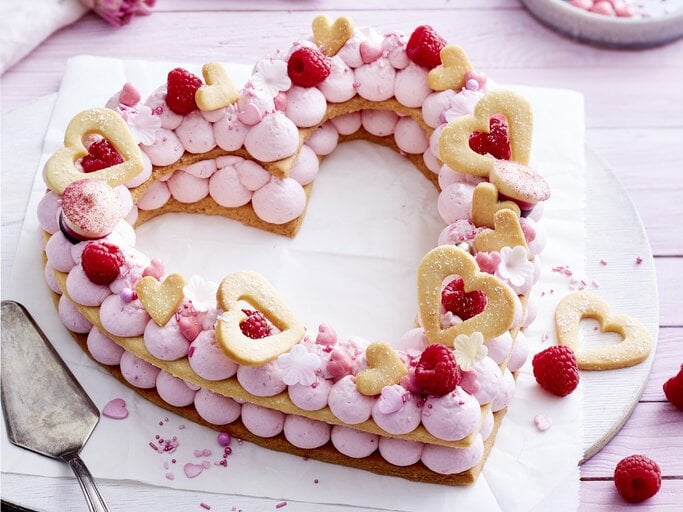 Auf einem Teller liegt ein Herz-Lettercake. Er ist dekoriert mit Zuckerperlen, Keks-Herzen, Himbeeren und rosa Creme.  | © EAT CLUB/Isabell Triemer
