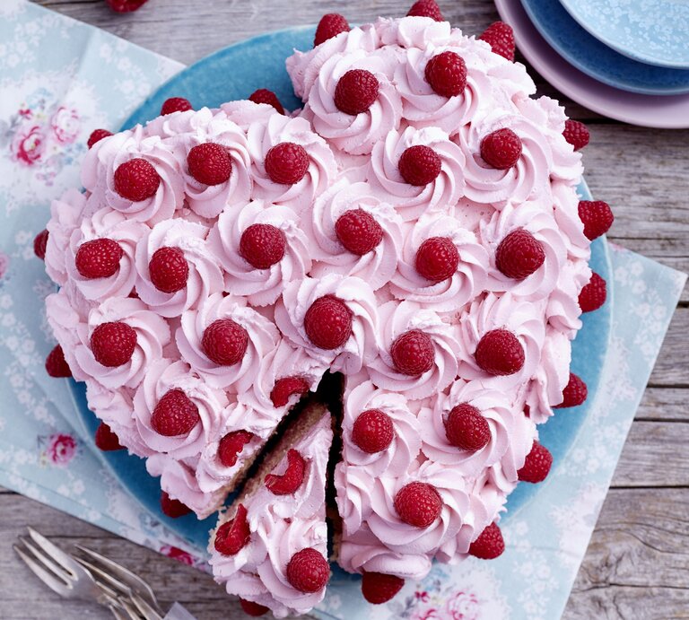 Herz-Himbeertorte auf einem blauen Teller auf hölzernem Hintergrund.  | © EAT CLUB/Isabell Triemer
