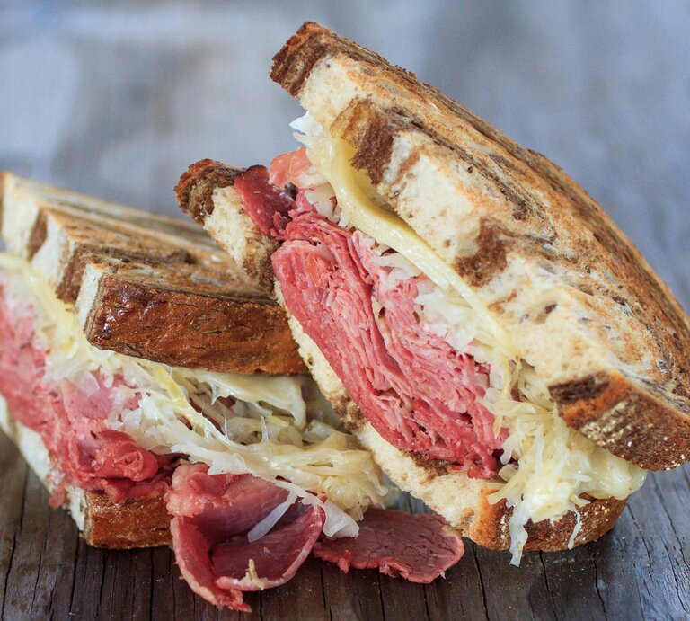 Ein halbiertes Pastrami Sandwich auf einem Holzuntergrund. Alles nah und von der Seite fotografiert. | © Gettyimages/ Jared Knetzer