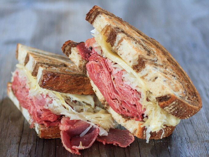 Ein halbiertes Pastrami Sandwich auf einem Holzuntergrund. Alles nah und von der Seite fotografiert. | © Gettyimages/ Jared Knetzer