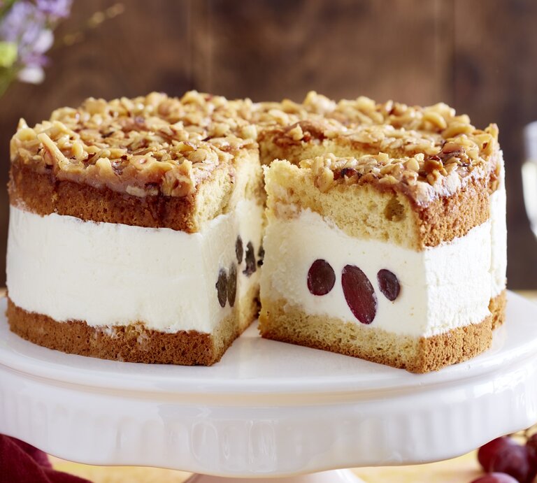Angeschnittene Weißwein-Trauben-Torte auf weißem Tortenteller, verschwommener Hintergrund.  | © EAT CLUB / Isabell Triemer 
