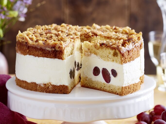 Angeschnittene Weißwein-Trauben-Torte auf weißem Tortenteller, verschwommener Hintergrund.  | © EAT CLUB / Isabell Triemer 