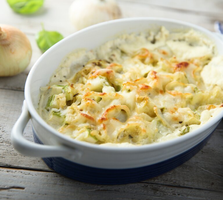 Blumenkohl-Zwiebel-Gratin in weißer Auflaufform auf hölzernem Untergrund.  | © Getty Images/Mariha-kitchen