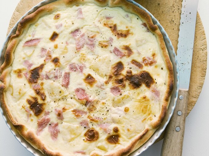 In einer runden Form ist eine Quiche Hawaii angerichtet. Sie ist mit Schinken und Ananas zubereitet. | © StockFood / Wissing, Michael