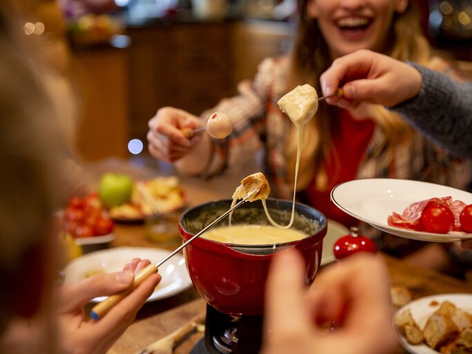 Menschen essen Käse-Fondue.  | © Getty Images/SolStock