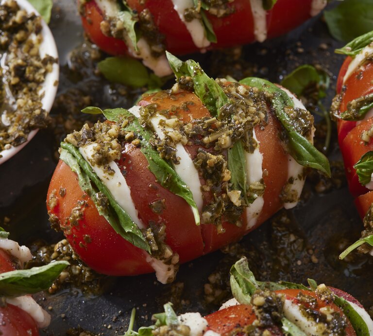 Fächer-Tomaten a la Caprese mit Knoblauch-Pesto serviert. | © Getty Images/ LauriPatterson