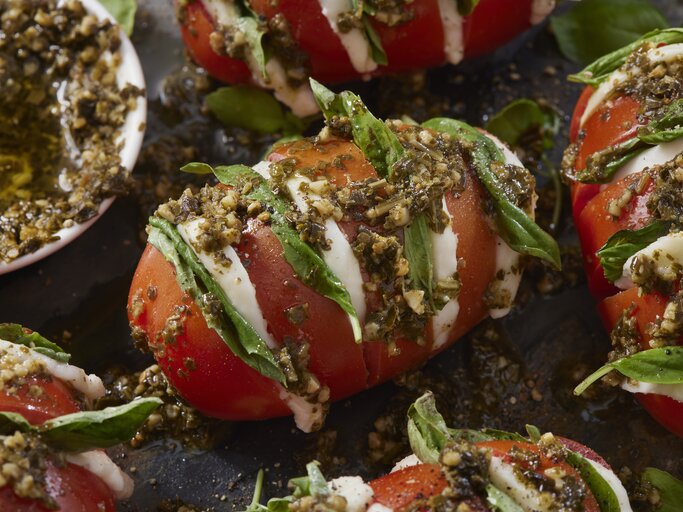 Fächer-Tomaten a la Caprese mit Knoblauch-Pesto serviert. | © Getty Images/ LauriPatterson
