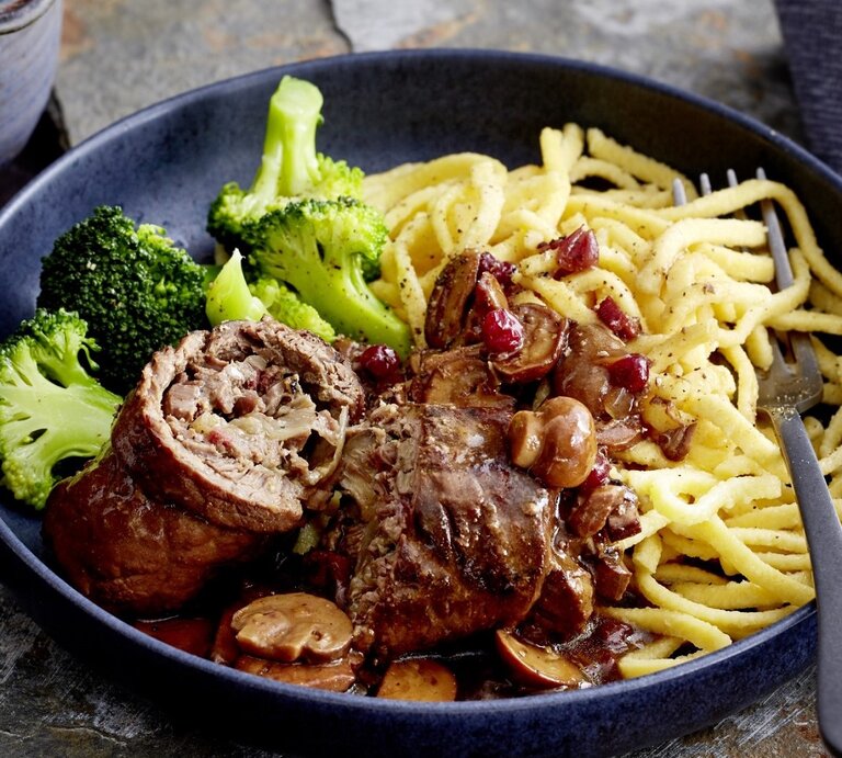 Auf einem tiefen Teller liegt eine Portion Rinderrouladen mit Pilzen und Spätzle. Sie wird mit Brokkoli serviert. | © EAT CLUB / Isabell Triemer