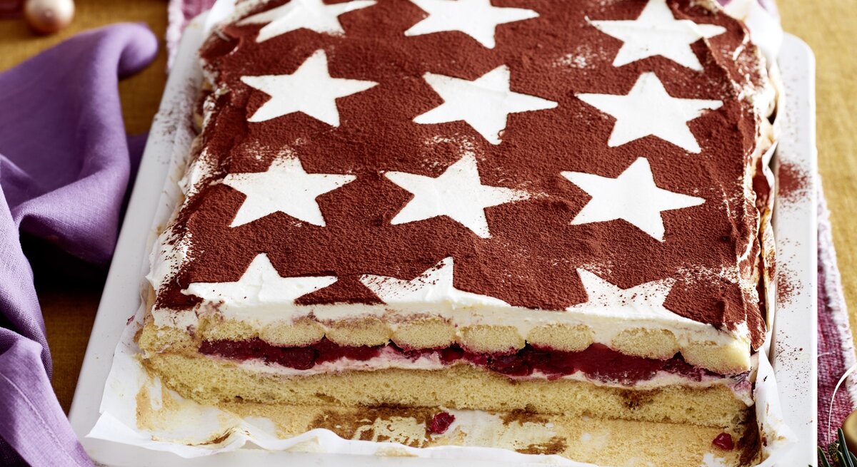 Glühwein-Tiramisu-Schnitten serviert auf einem weißen Teller, daneben weihnachtliche Deko-Elemente. 