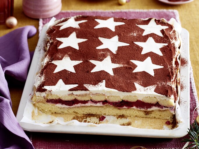 Glühwein-Tiramisu-Schnitten serviert auf einem weißen Teller, daneben weihnachtliche Deko-Elemente.  | © EAT CLUB/Isabell Triemer