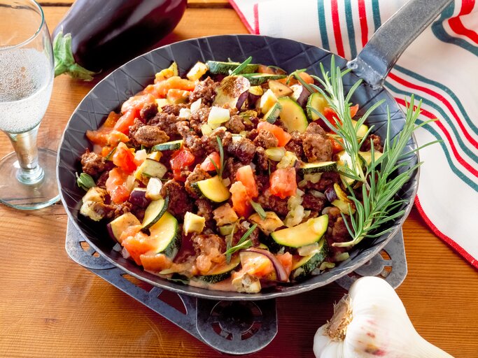 Zucchini-Hackfleisch-Pfanne mit Tomaten auf Holztisch.  | © Shutterstock/Jack Jelly