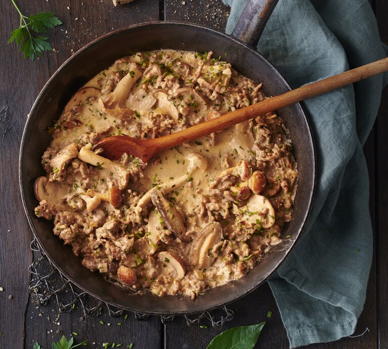 Hackfleisch-Jägerpfanne mit  gemischten Pilzen und frischen Kräutern. Das Gericht befindet sich in einer rustikalen Pfanne und besteht aus gebräuntem Hackfleisch gemischt mit einer Vielzahl von Pilzen, die in verschiedenen Größen und Formen zu sehen sind. Die Pilze sind goldbraun geröstet. | © GettyImages/Seefoodstudio