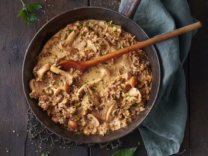 Hackfleisch-Jägerpfanne mit  gemischten Pilzen und frischen Kräutern. Das Gericht befindet sich in einer rustikalen Pfanne und besteht aus gebräuntem Hackfleisch gemischt mit einer Vielzahl von Pilzen, die in verschiedenen Größen und Formen zu sehen sind. Die Pilze sind goldbraun geröstet. | © GettyImages/Seefoodstudio