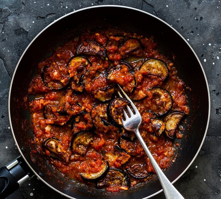 Eine schwarze Pfanne auf dunklem Steinuntergrund mit der Auberginenpfanne. | © Shutterstock/ Kiian Oksana 
