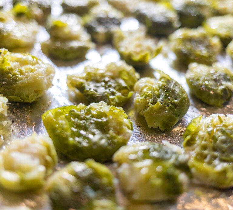 Smashed Rosenkohl auf einem Backblech mit Backpapier. | © Getty Images/ carlofranco