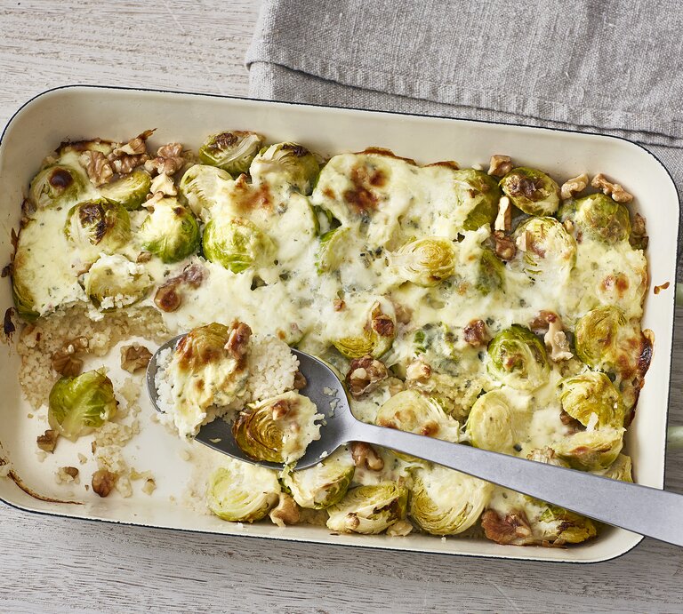 Ofencouscous mit Rosenkohl, Walnüssen und überbackenem Blauschimmelkäse in einer Form auf hellem Untergrund  | © Stockfood