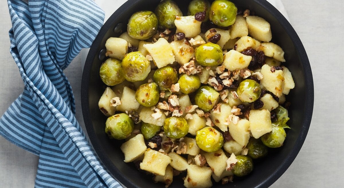 Rosenkohl-Gnocchi-Pfanne mit Walnüssen auf hellem Untergrund. 