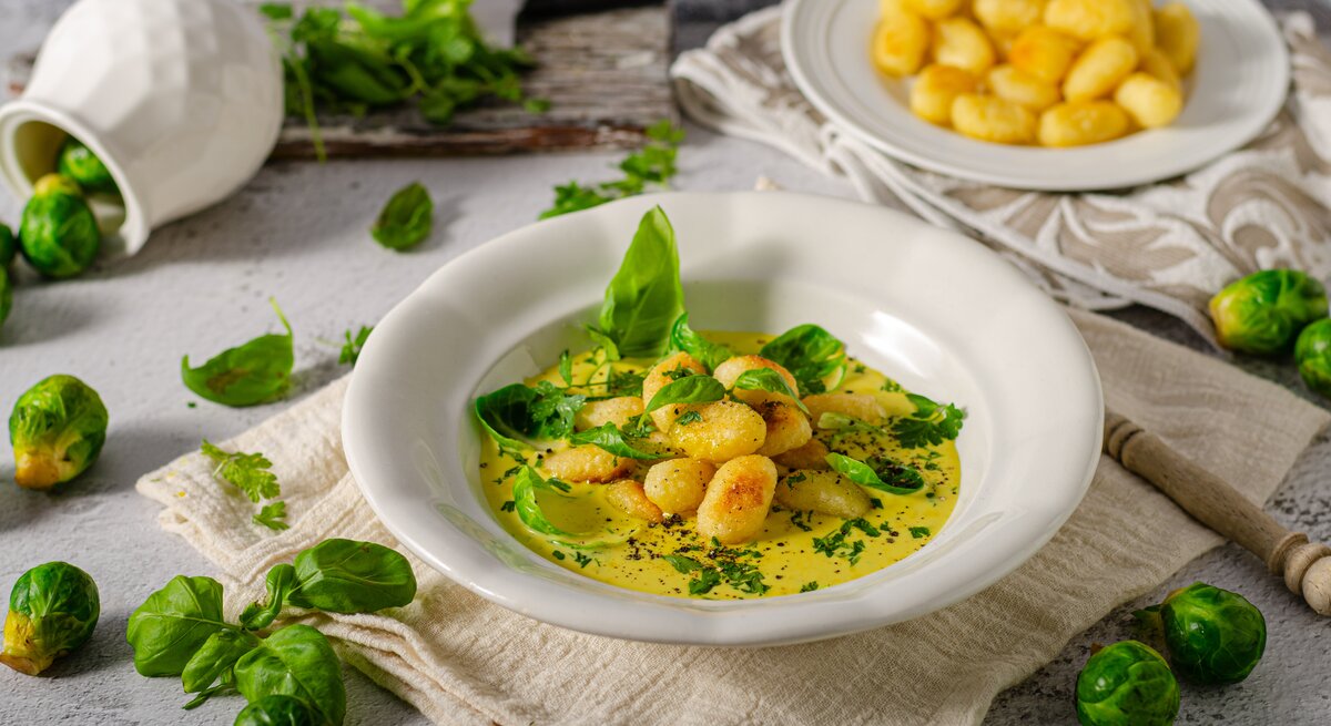 Gnocchi in Rosenkohl-Curry auf weißem Teller. 