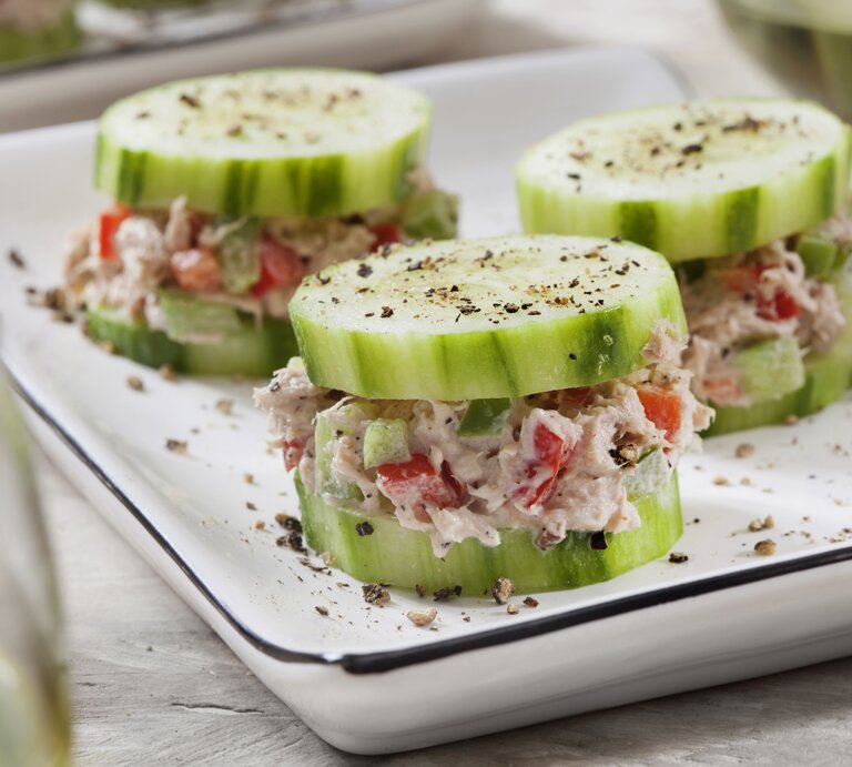 Auf einer weißen Porzellanschale sind drei kleine Gurken-Häppchen mit Thunfisch. Es handelt sich um Fingerfood. | © Getty Images / LauriPatterson