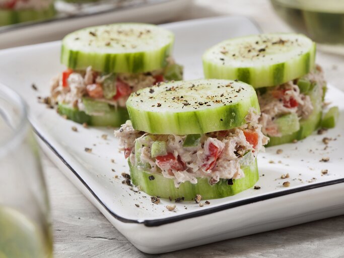 Auf einer weißen Porzellanschale sind drei kleine Gurken-Häppchen mit Thunfisch. Es handelt sich um Fingerfood. | © Getty Images / LauriPatterson