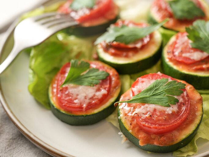 Zucchini-Bruschetta-Häppchen auf einem Teller, daneben eine Gabel. | © Adobe Stock/ Maren Winter