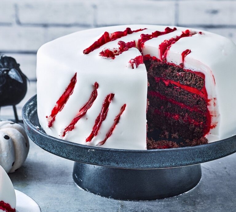Auf einem Tortenteller steht eine gruselige Halloween-Torte. Sie ist mit weißem Fondant eingedeckt und hat blutige Risse als Dekoration. | © StockFood / Immediate Media / Good Food