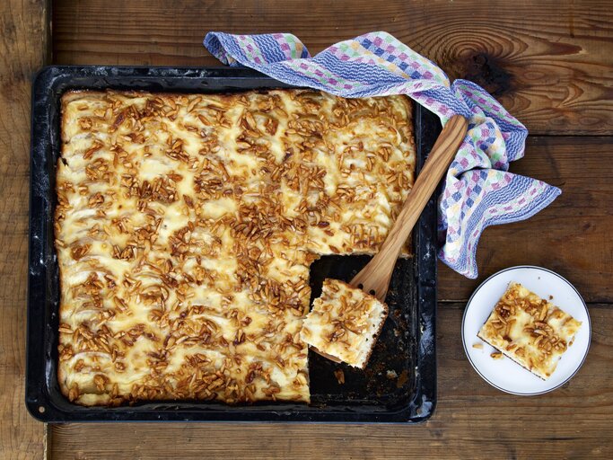 Apfelkuchen vom Blech mit Krokant, angeschnitten auf dem schwarzen Ofenblech serviert.  | © StockFood / für ZS Verlag / Skowronek, Julia