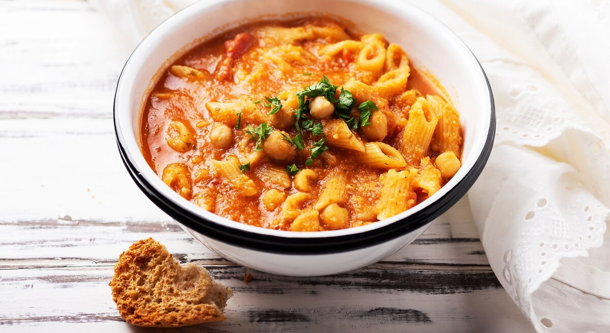 Eine Schüssel Pasta e Ceci, italienischer Nudeleintopf mit Kichererbsen, garniert mit Petersilie.
