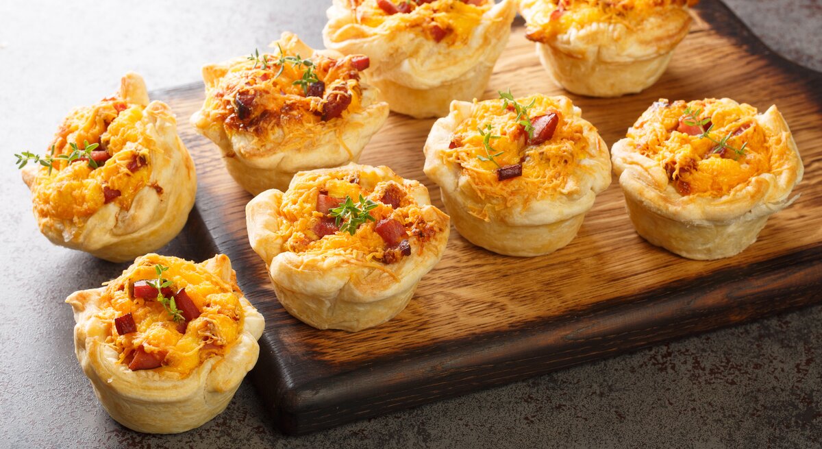 Blätterteig-Muffins mit Schinken & Käse auf Holzbrett. 