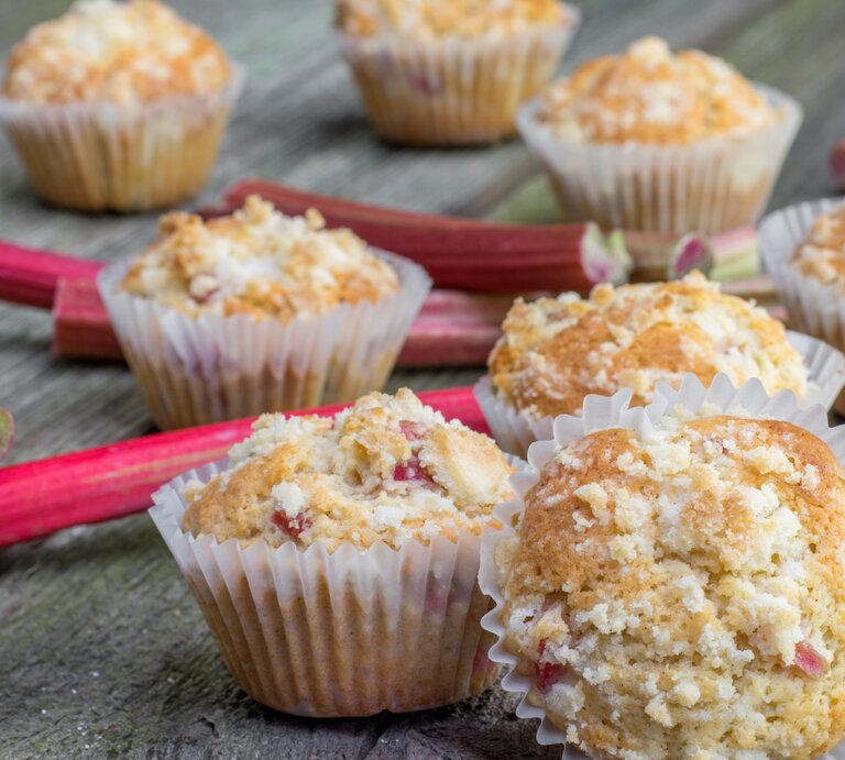 Mehrere Muffins auf einem Holztisch mit Rhabarberstangen. | © Shutterstock/ Jaromir Klein