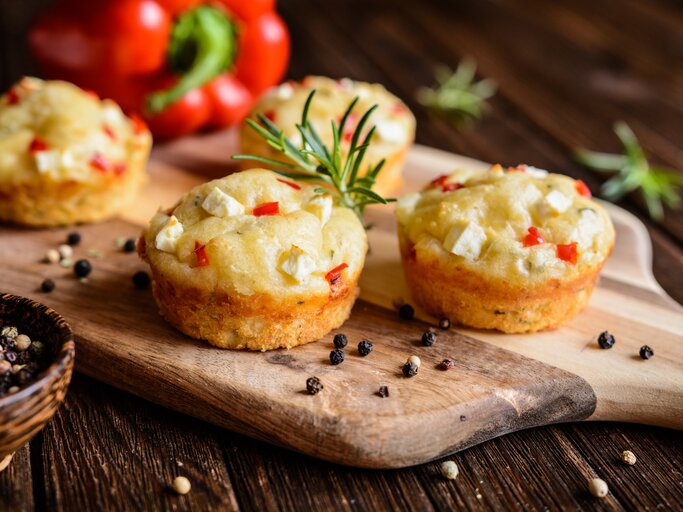 Feta-Muffins mit Paprika auf einem Holzschneidebrett neben einer Paprika | © Getty Images/NoirChocolate