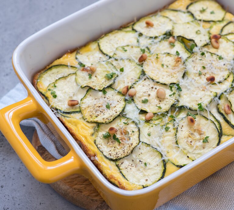 Zucchini-Auflauf mit Hackfleisch und Feta in gelber Auflaufform auf hellem Untergrund.  | © Getty Images/Azurita