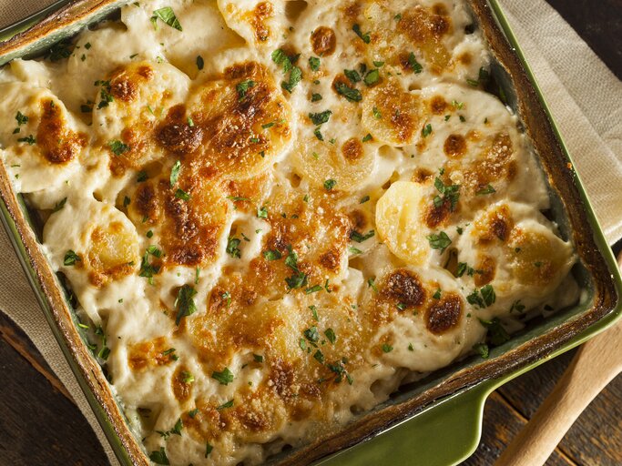Kartoffelauflaf mit Käse und Petersilie in grüner Auflaufform.  | © Getty Images/bhofack2