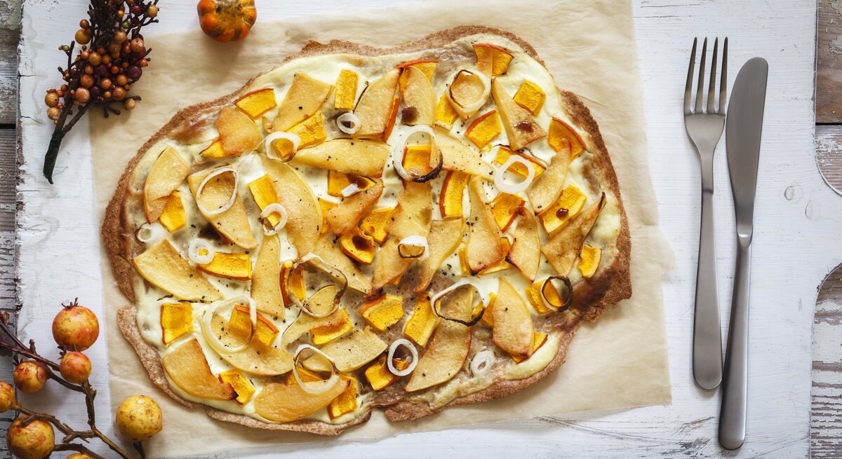 Kürbis-Quitte-Flammkuchen auf Holzbrett.