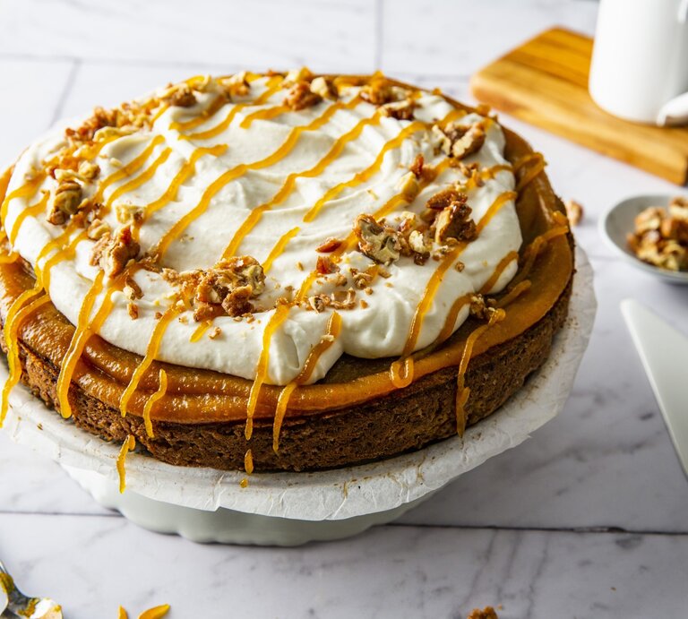 Kürbiskuchen mit Frischkäsecreme und gebrannten Walnüssen, garniert mit Karamell und serviert auf einer großen Kuchenplatte auf einem weißen Fliesentisch.  | © StockFood / Krimshandl-Tauscher, Sandra