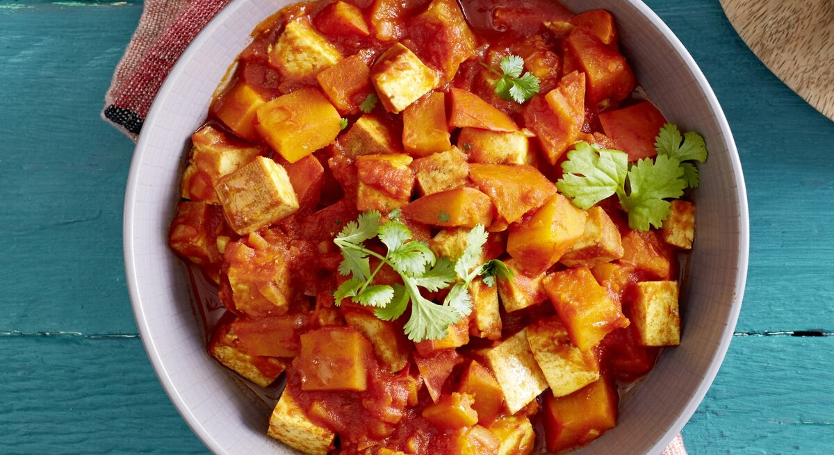 Ein Teller Kürbis-Tofu-Ragout mit Petersilie bestreut, Draufsicht.