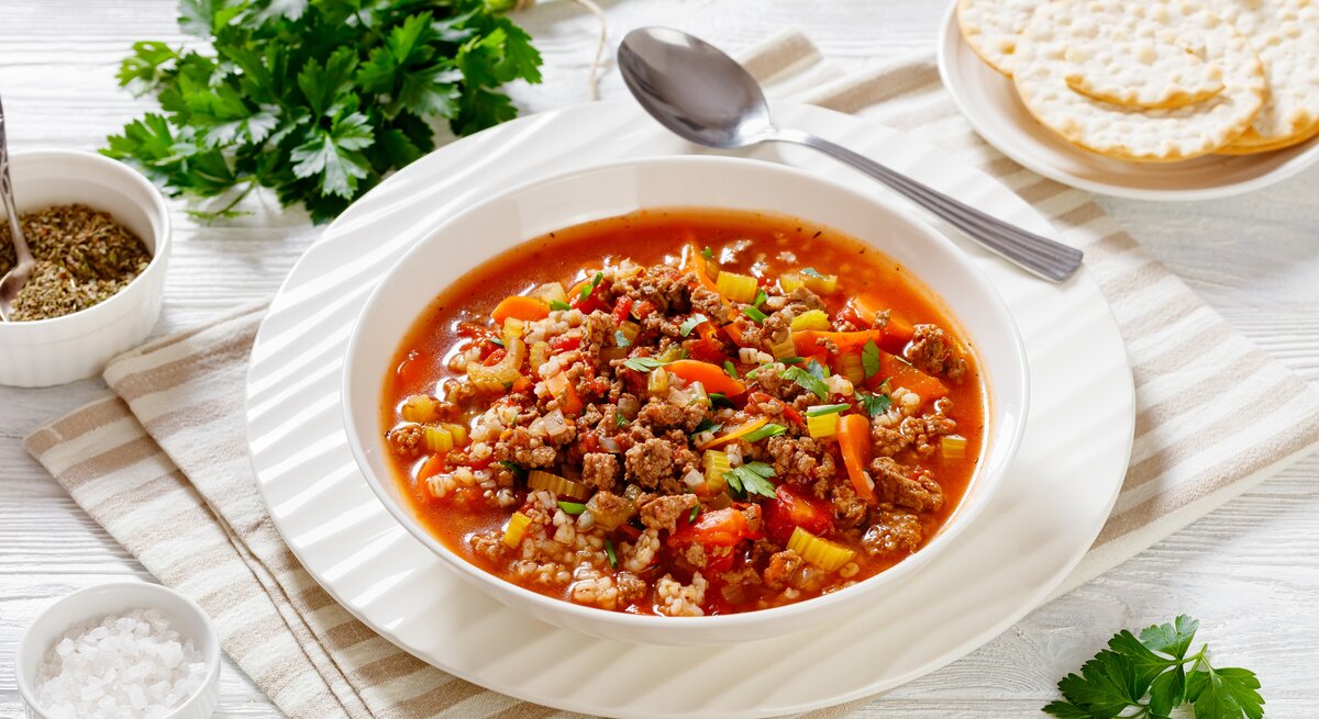 Tomatige Hackfleisch-Suppe auf weißem Teller. 